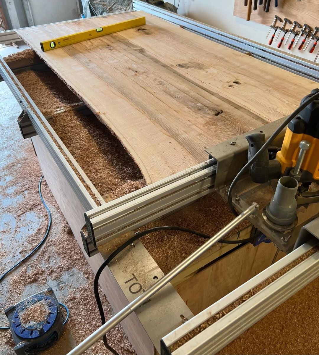 An ash table top being flattened on a router sled