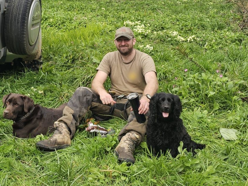 Jon sitting in a field with two dogs